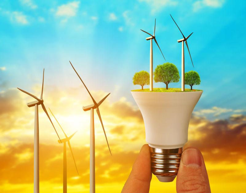 生态LED灯泡与风力涡轮机手在日落