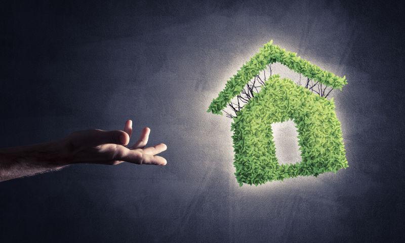 商人手和绿色住宅图标作为建筑节能的象征