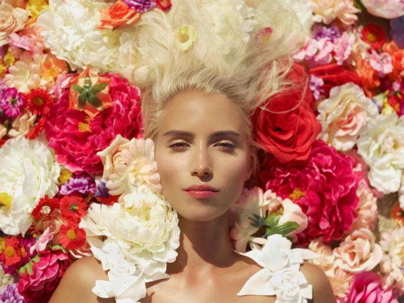 躺在白色和红色花朵上的金发美女