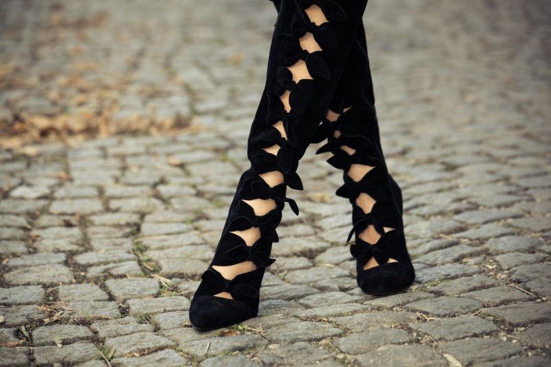 鹅卵石路面上黑色秋千高跟鞋中的美女腿