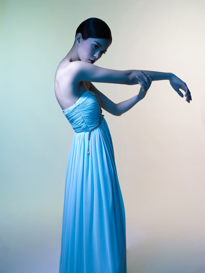 灰色背景上穿着蓝色长裙的美女模特