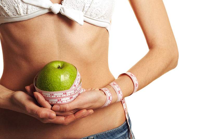 在她肚子前拿着节食的女人吃苹果