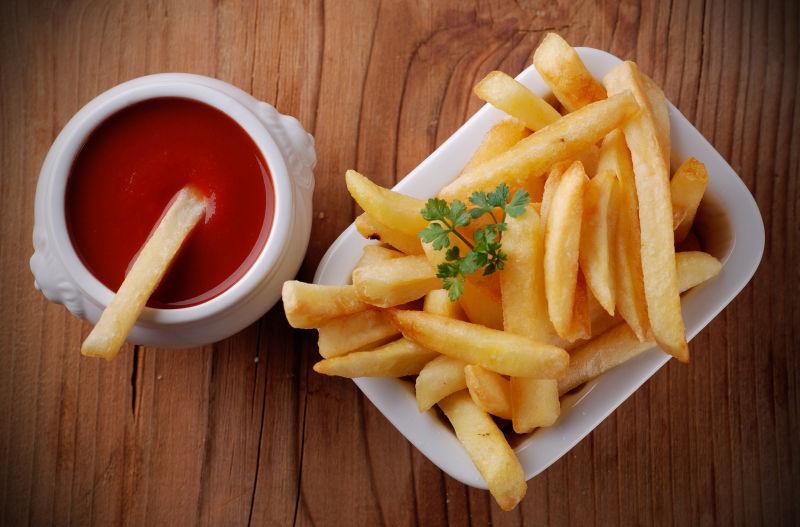 木桌上的美味炸薯条和番茄酱