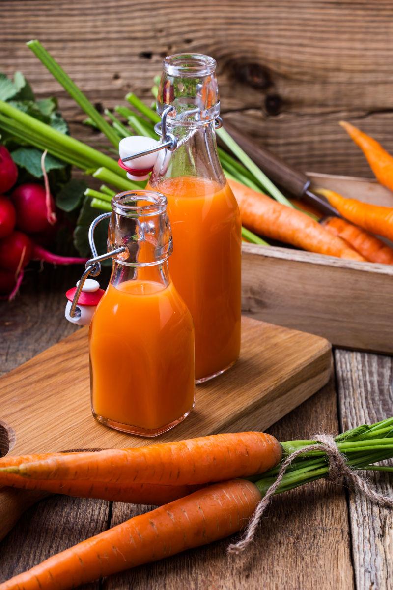 木板上的两瓶新鲜胡萝卜汁