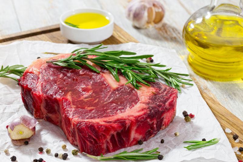 生牛肉在木制砧板上用迷迭香蒜瓣和胡椒粉混合