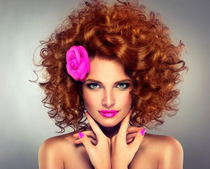 美丽的红色卷发和粉红指甲的性感女孩