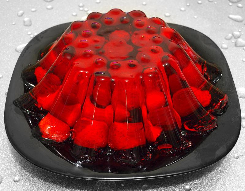 放在黑色盘子里的鲜红色草莓果冻布丁