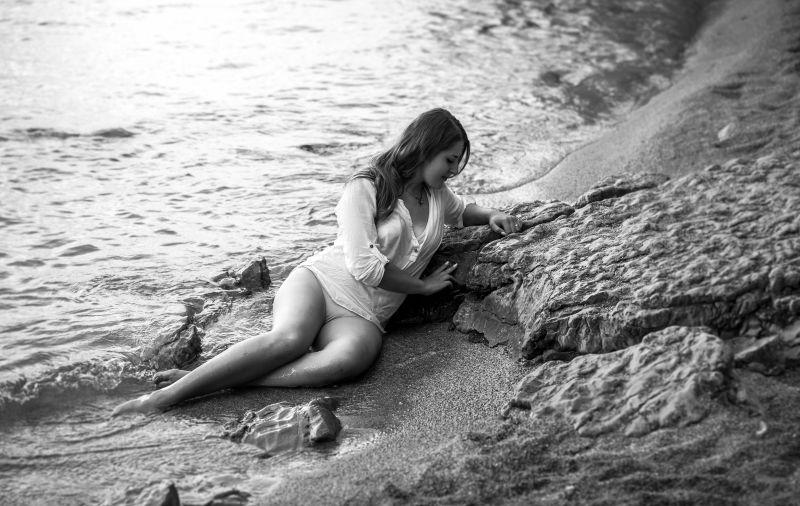 斜坐在海边沙滩上的美女