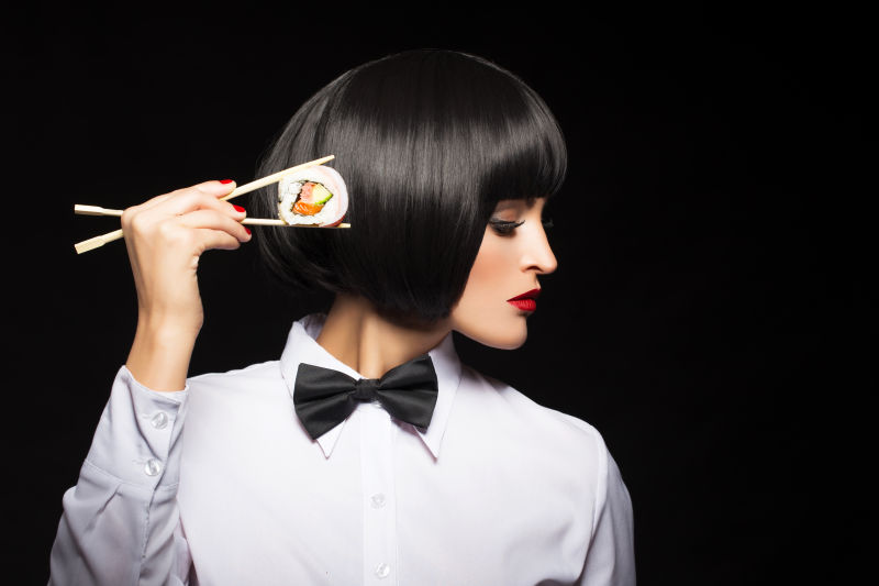 穿着白色衬衫的美女夹着一块寿司