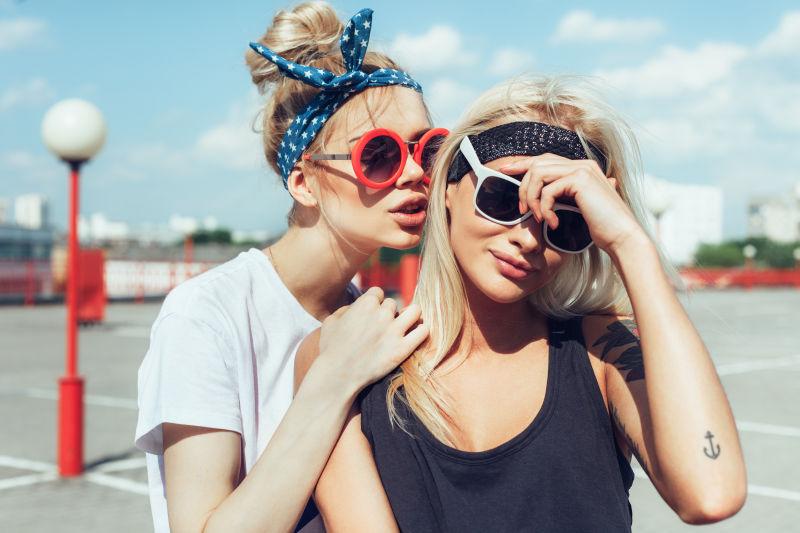 城市背景带着时尚太阳镜的两个女孩
