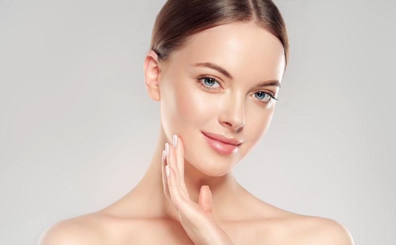 美丽的年轻女子触摸着自己的脸