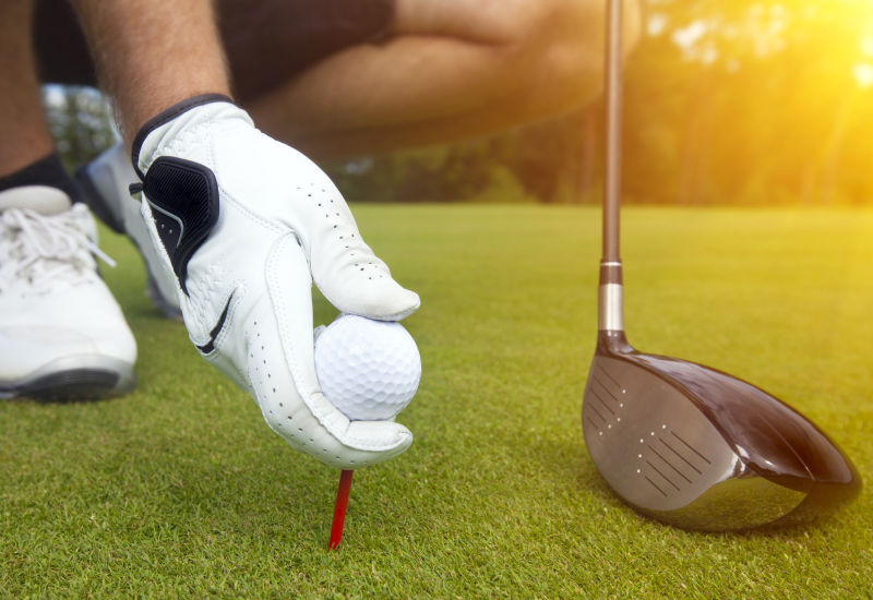 一双手把高尔夫球放在球座上