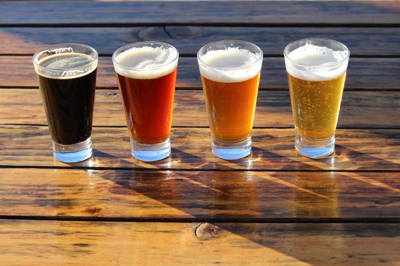 木桌上的四杯不同颜色的啤酒