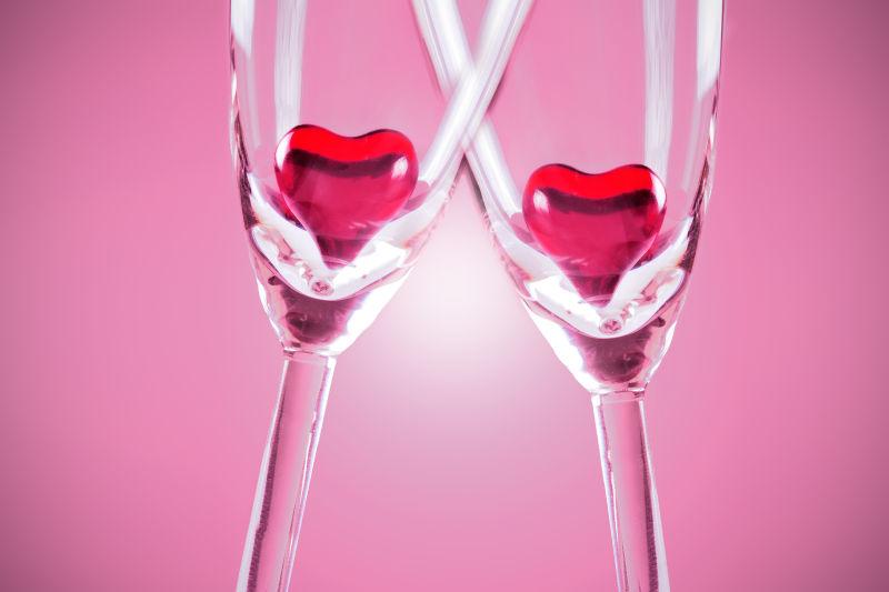 两个放着红色爱心的玻璃高脚杯