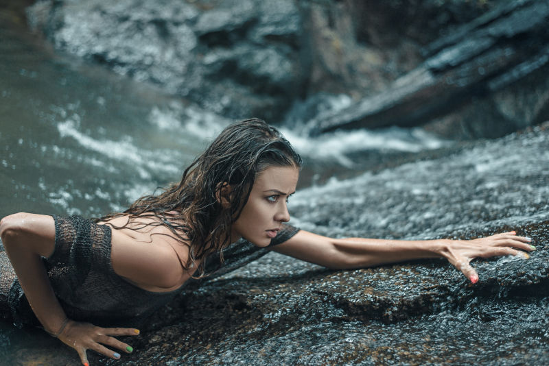 性感女人在潮湿的岩石上攀爬