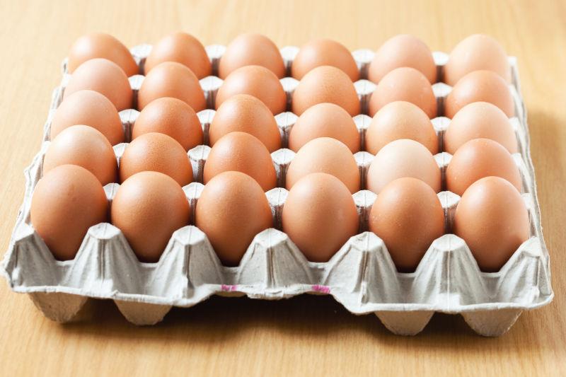 木纹理桌上的拖着鸡蛋的鸡蛋托盘