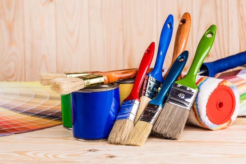 木制背景上的油漆辊和油漆刷