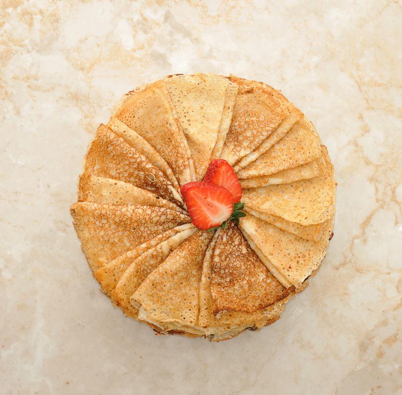 折叠的三角形煎饼上的草莓在大理石背景上