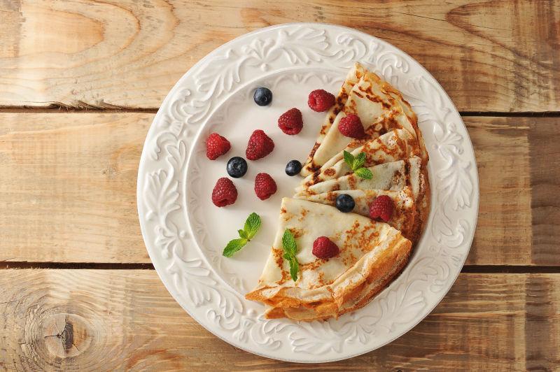 木桌上盘里的薄煎饼和浆果