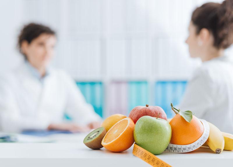 职业营养学家在办公室会见病人和健康水果带前台