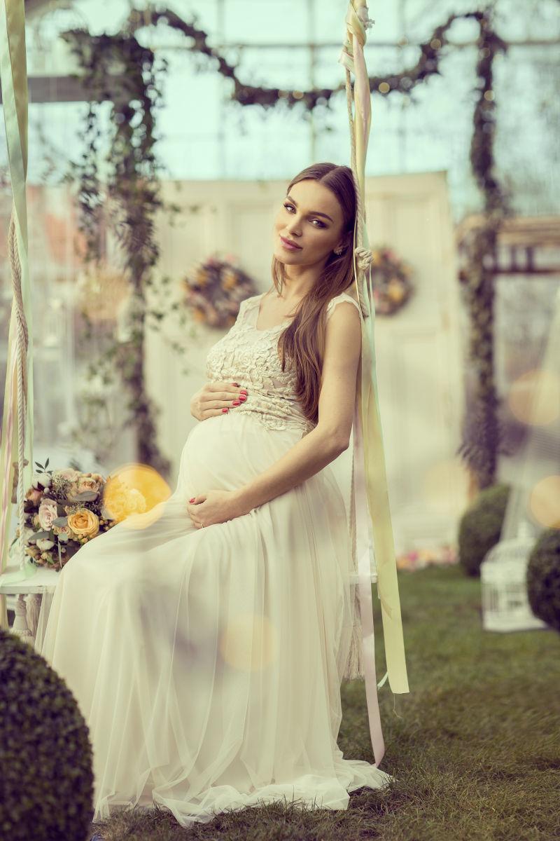 坐在秋千上的怀孕的孕妇