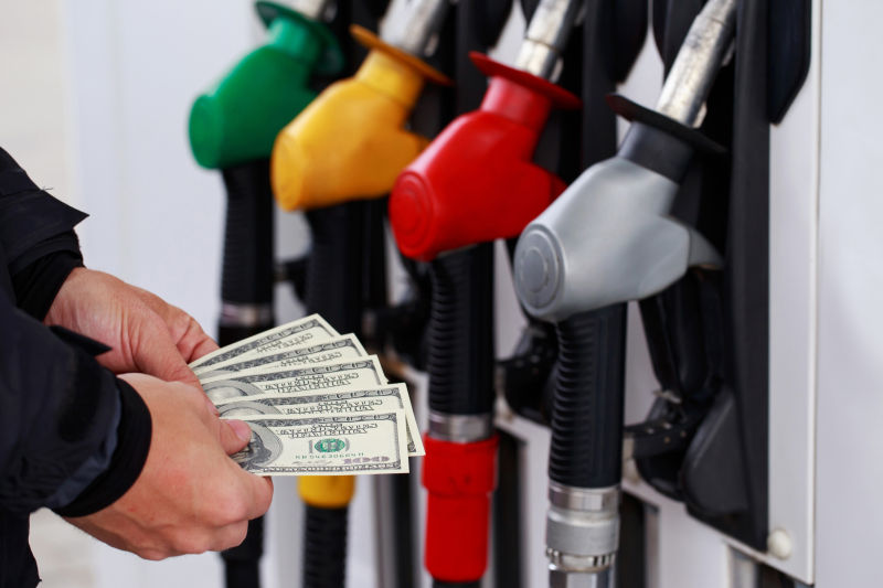 加油枪前拿着美元的男人