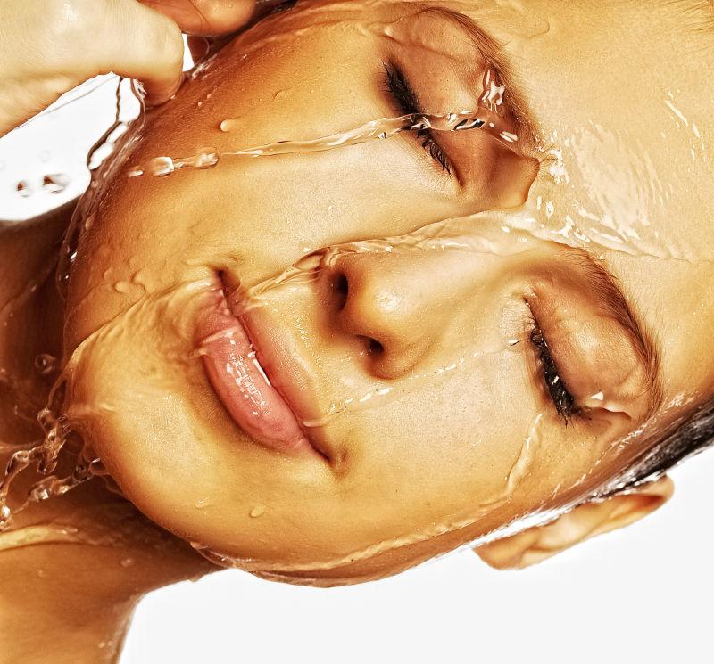 白色背景下用水洗脸的美女