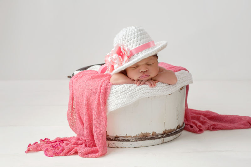 戴着帽子趴在木桶里睡觉的婴儿
