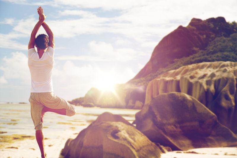 坐在瑜伽树上的人在沙滩上冥想