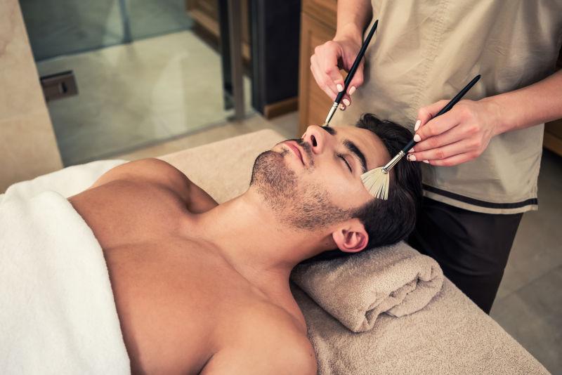 男性在按摩床上享受面部按摩