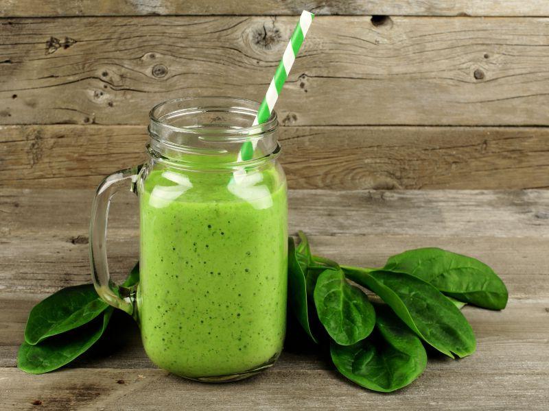 木桌上玻璃杯里美味的菠菜冰沙