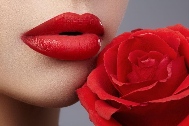 美女红色嘴唇边的玫瑰花