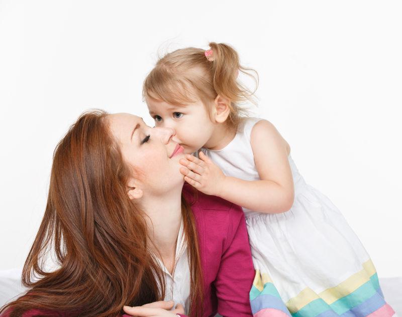 可爱的小女孩亲吻妈妈的脸颊