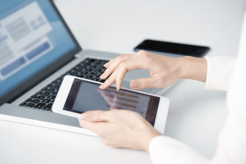 女商人使用平板电脑和笔记本电脑查阅图标