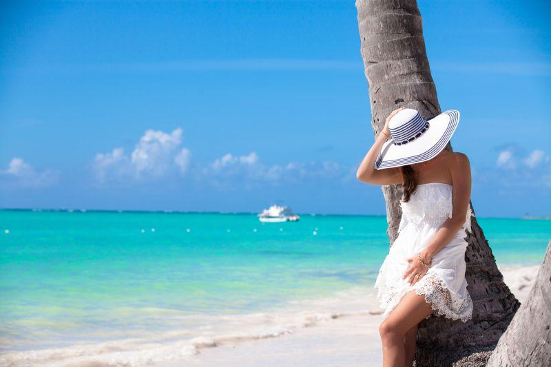 海滩上靠在树上的的年轻女子