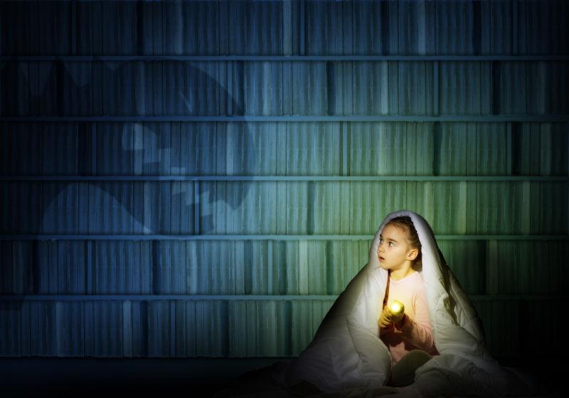 裹着被子拿着手电筒的女孩