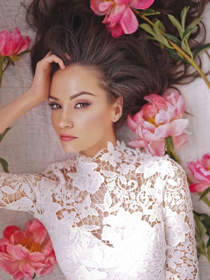 散落头发躺着的穿着白色蕾丝衣服的美女