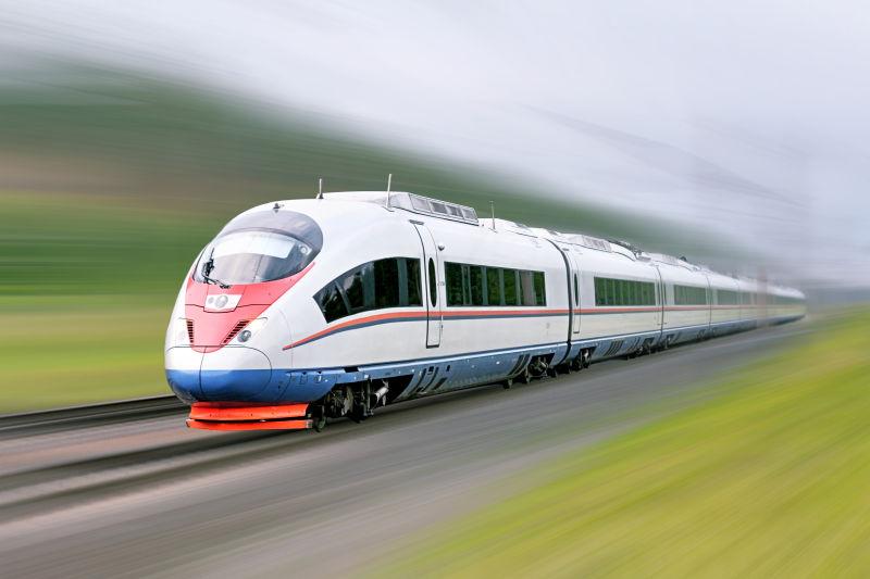 绿色背景上铁轨上高速行驶的超流线型列车