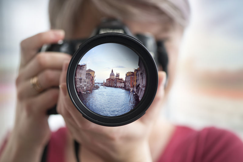 拿着相机拍摄旅游景点的女人