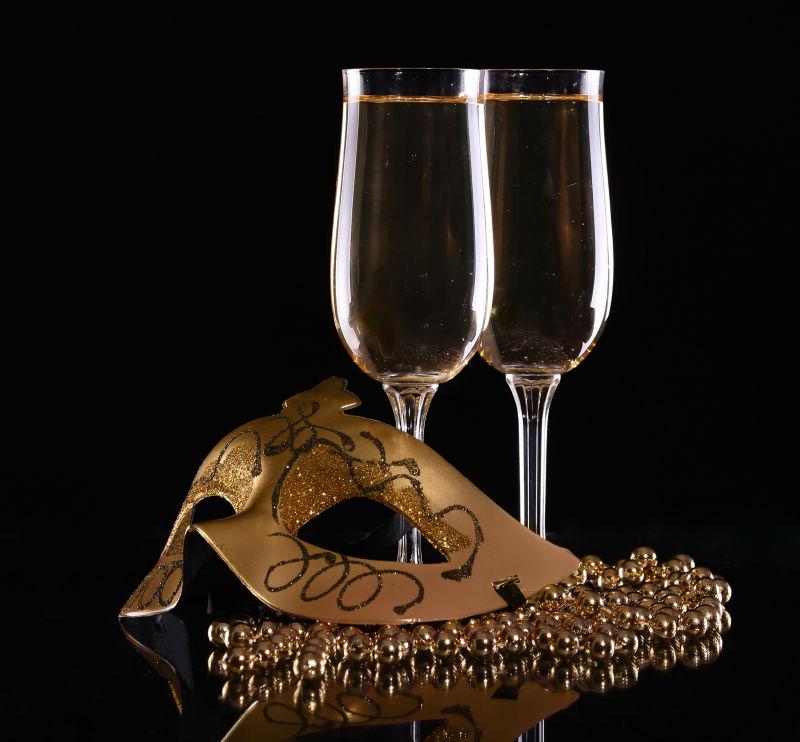 黑暗背景下的高脚杯里的酒和面具