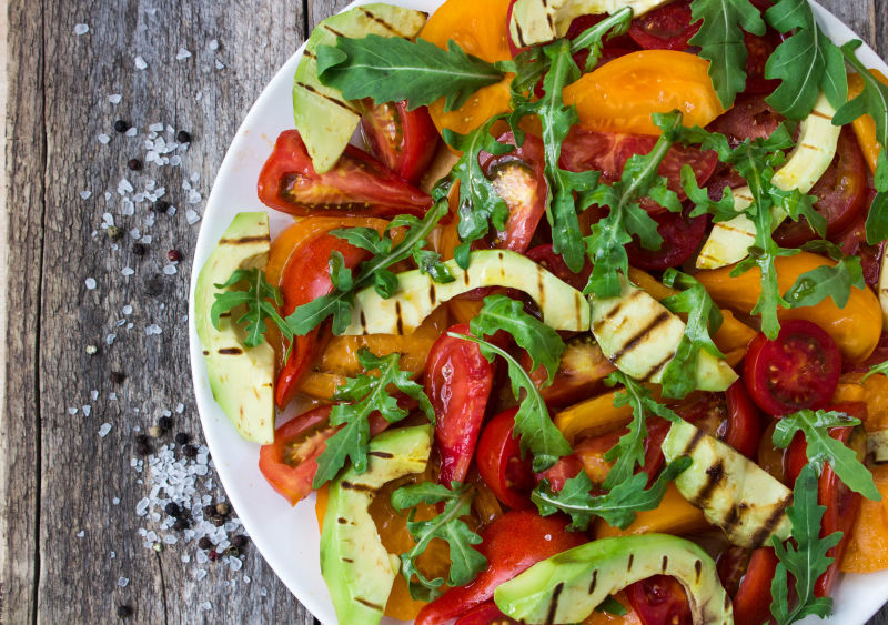 木制背景上的鳄梨和番茄沙拉