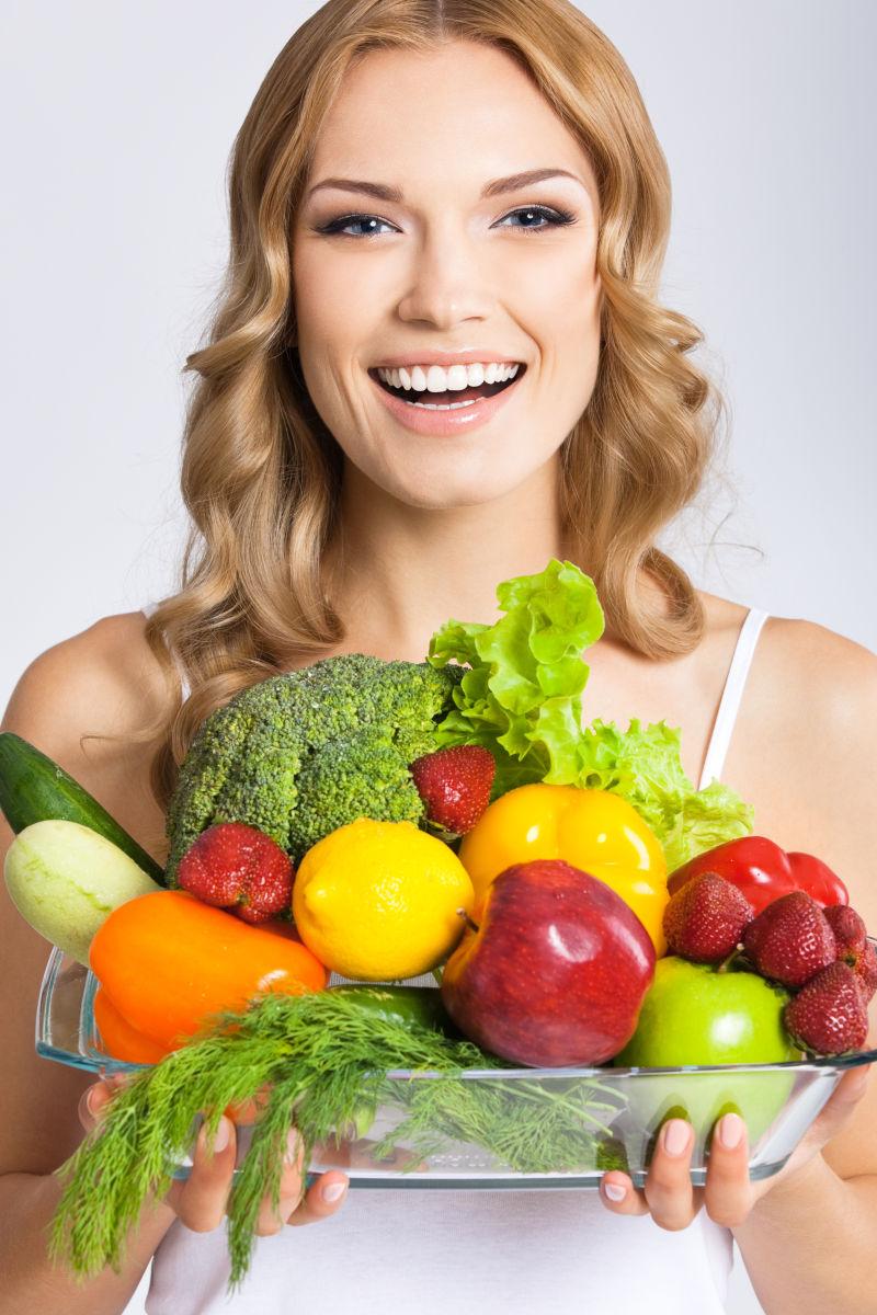 年轻美女抱着健康蔬菜和水果