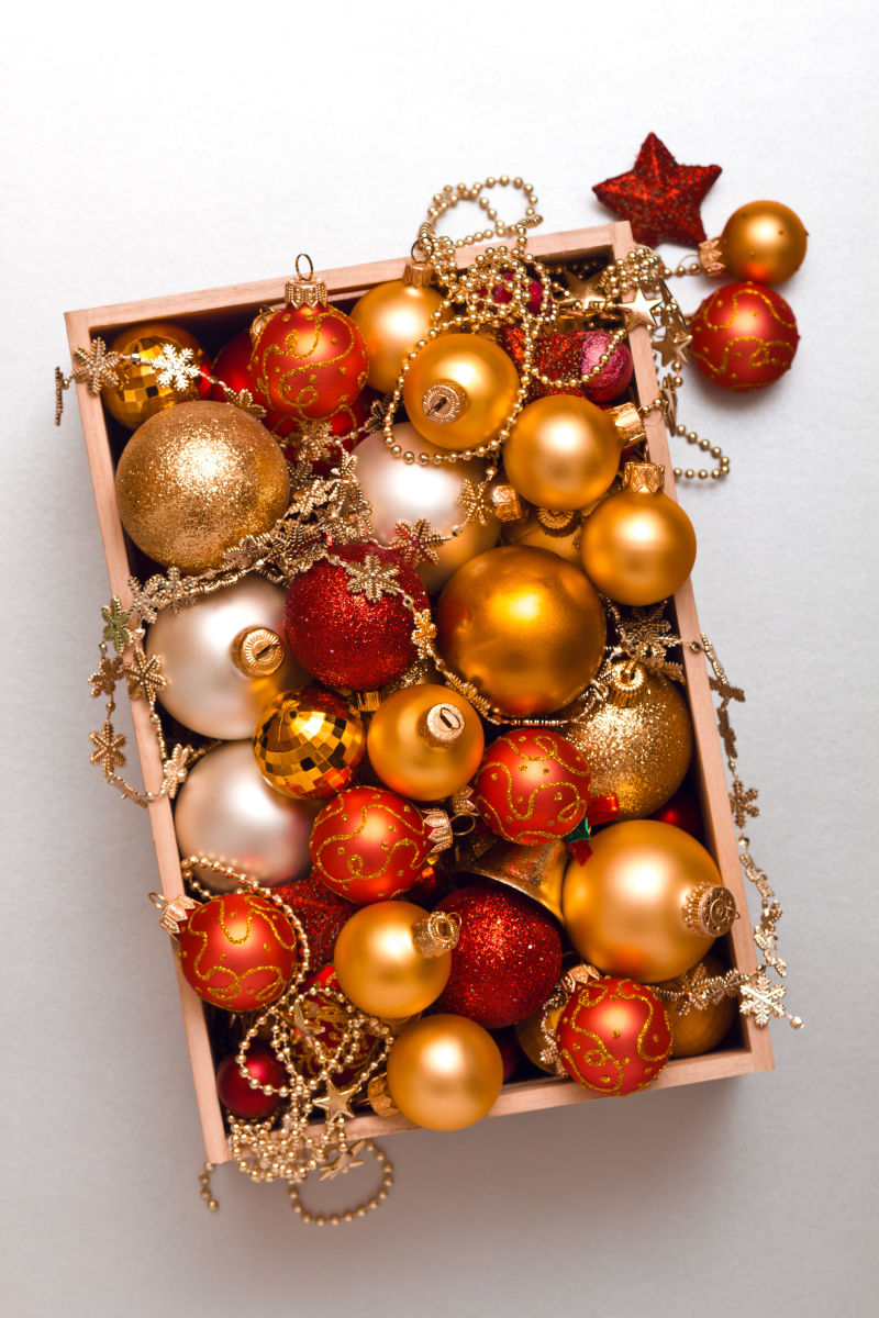 白色背景上的木箱里金色和红色的圣诞彩球