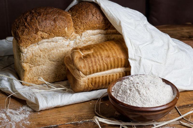 木桌上的小麦面包和小麦面粉