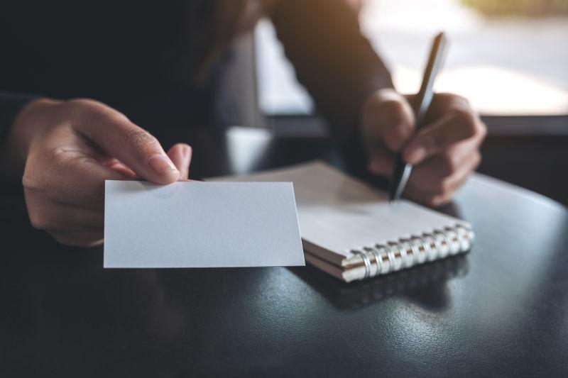 在办公桌上记笔记和出示名片的商人