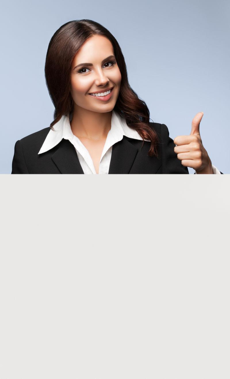 穿着黑色西装的年轻女商人显示拇指向上手势