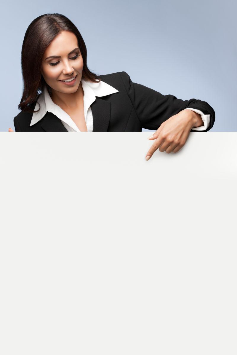 穿着黑色西装的年轻女商人标示空白标牌