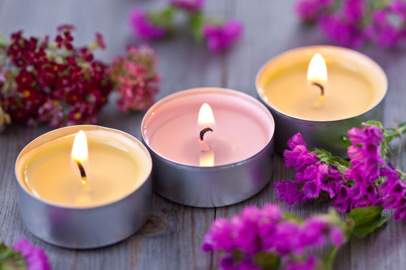 木质板上花瓣旁彩色的蜡烛