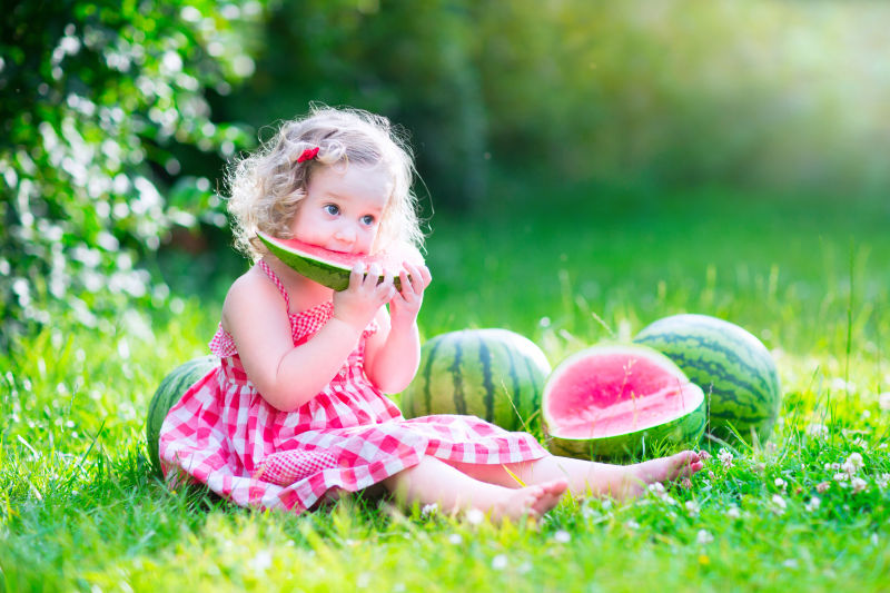 草地上吃西瓜的小女孩
