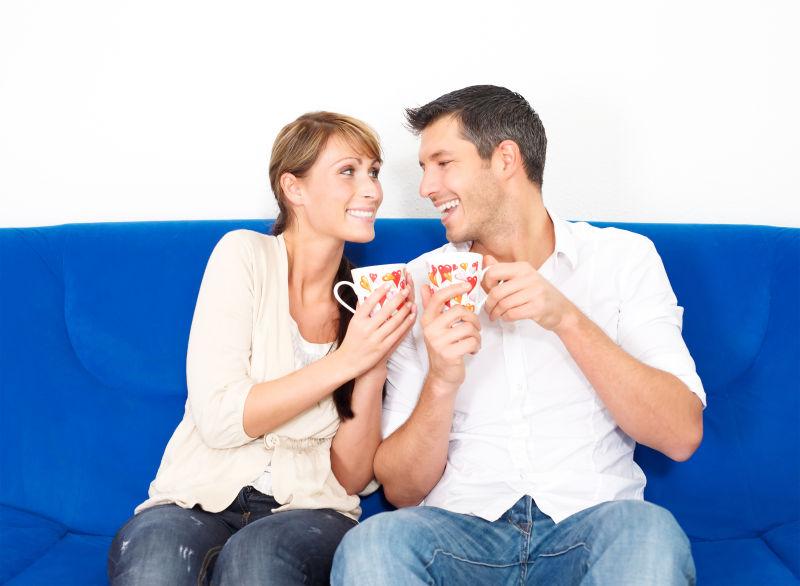 蓝色沙发上喝着咖啡的快乐情侣